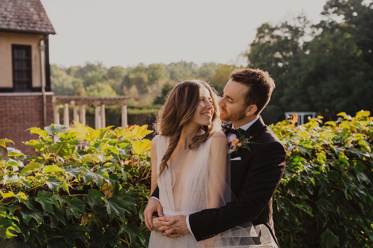 Couple embraces in front of hedge at Virginia wedding