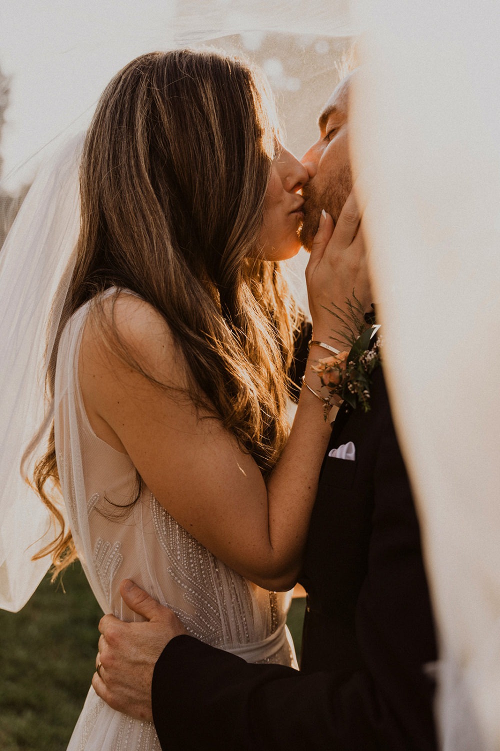 Couple kisses under veil while captured by wedding videographer