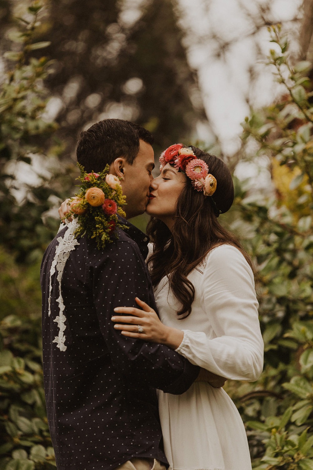 Couple kisses while holding spring wedding flowers