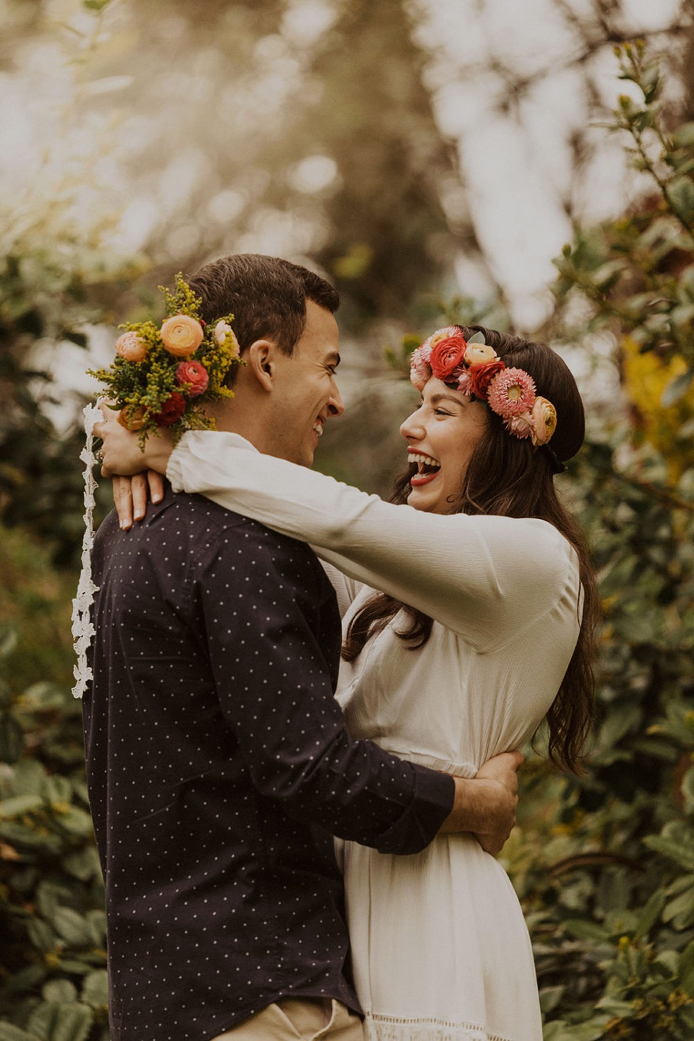 Couple embraces while holding spring wedding flowers