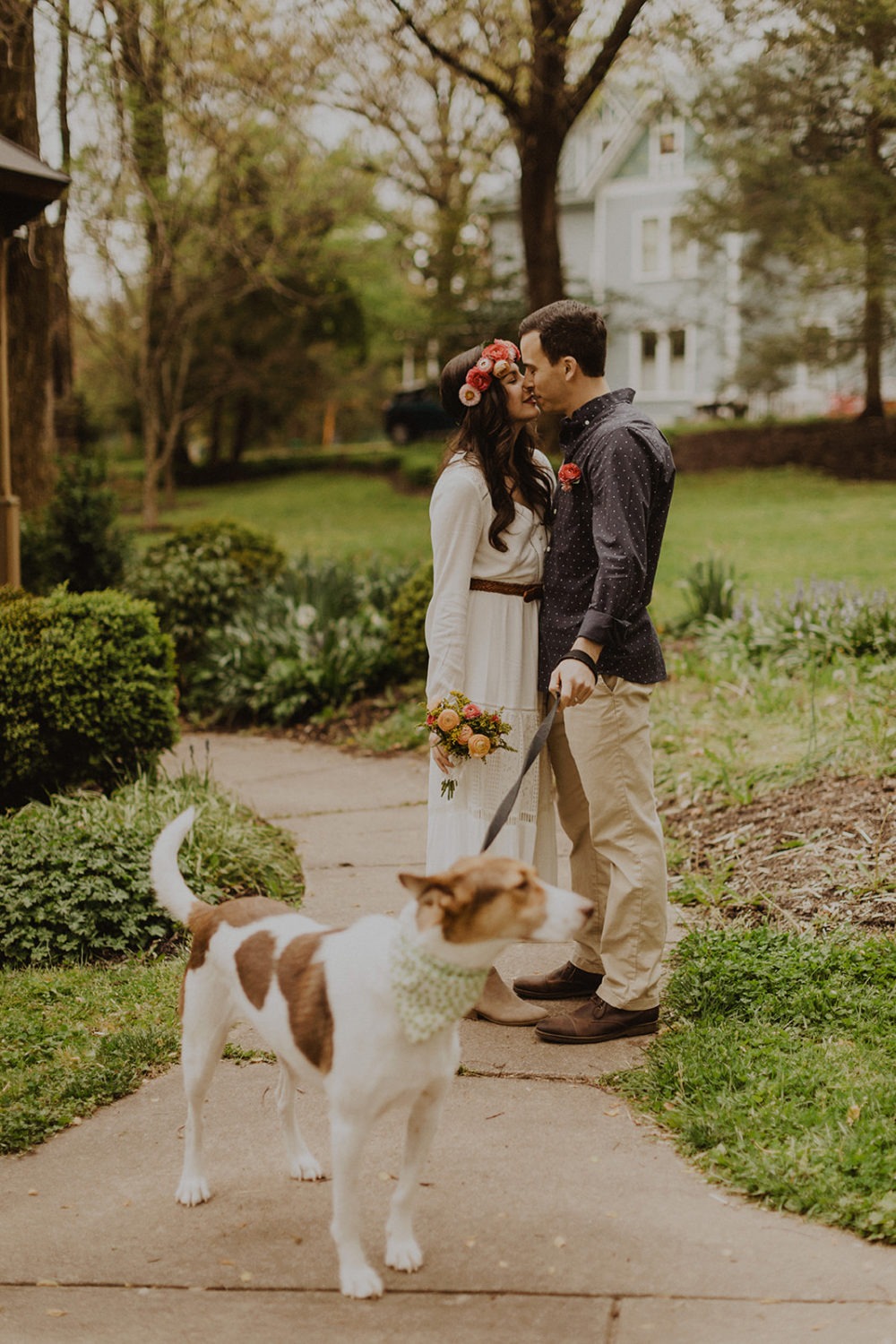 Couple kisses with dog on leash at spring Virginia park elopement