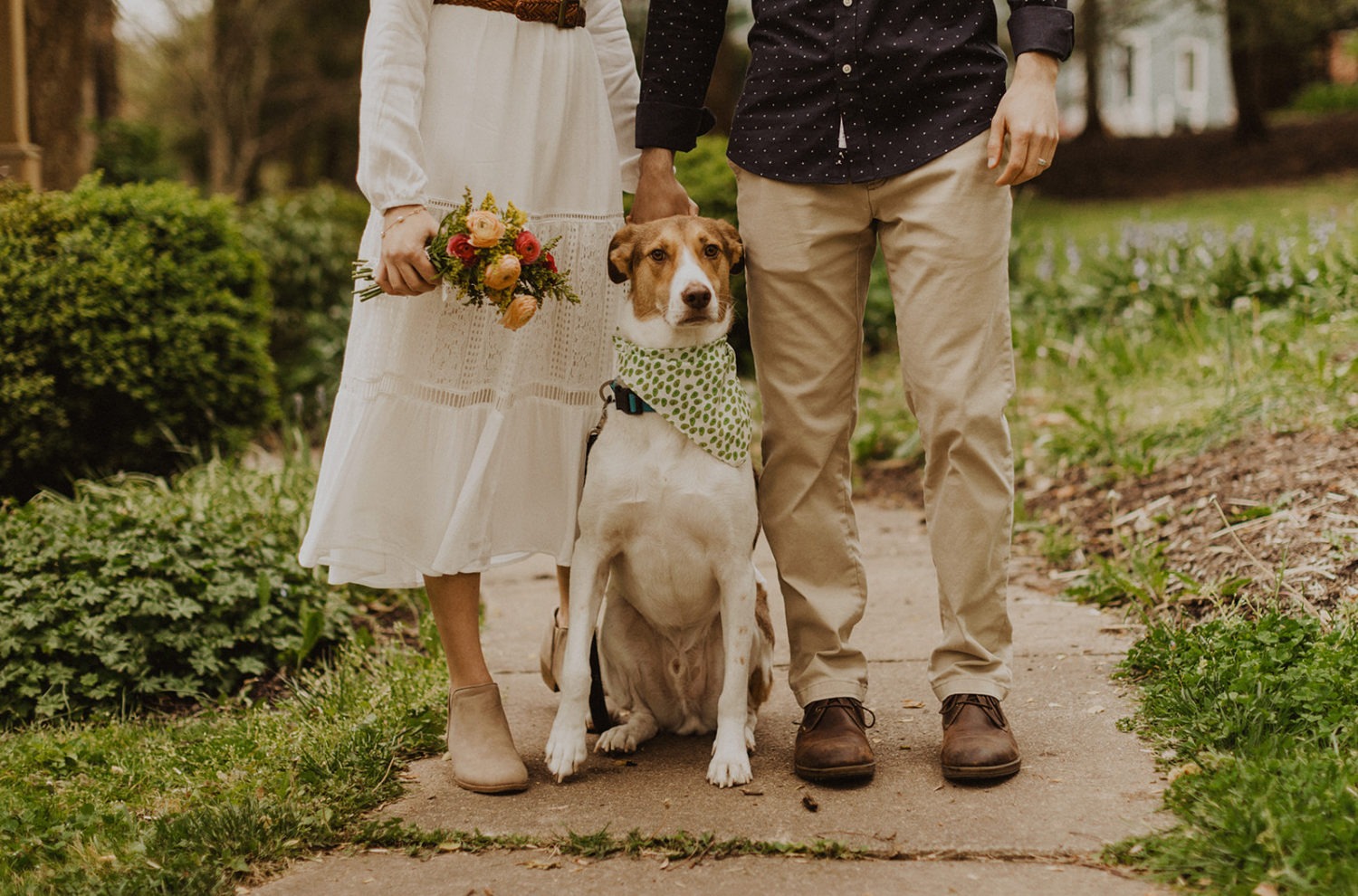 Couple stands by dog holding spring wedding flowers 