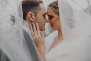 Couple embraces under wedding veil