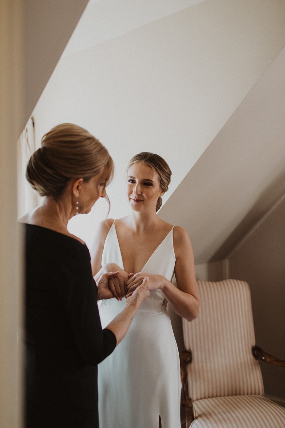 Mom holds bride's hands as she gets ready for her intimate wedding