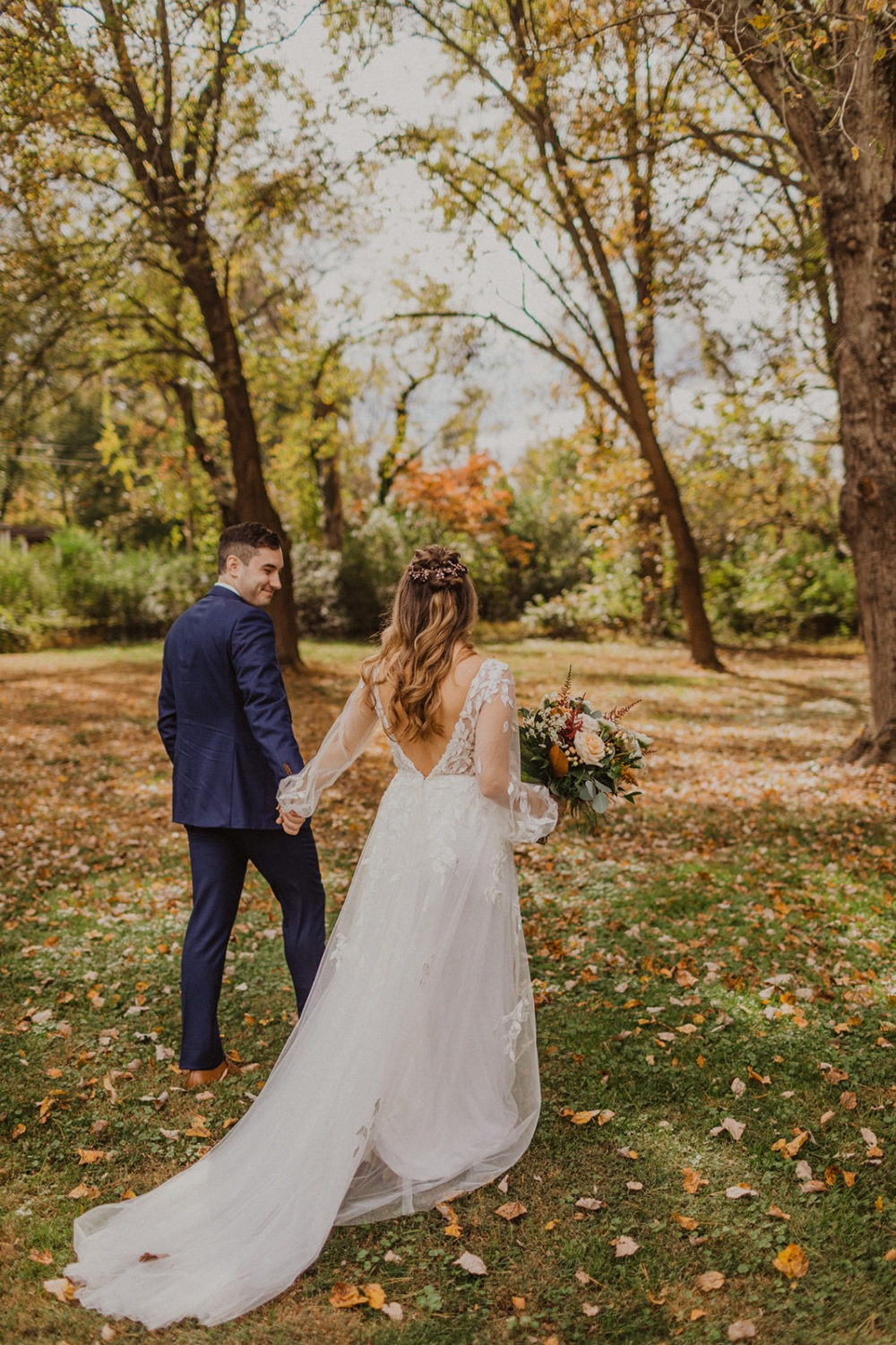 Couple holds hands while waking through woods at Virginia wedding venue