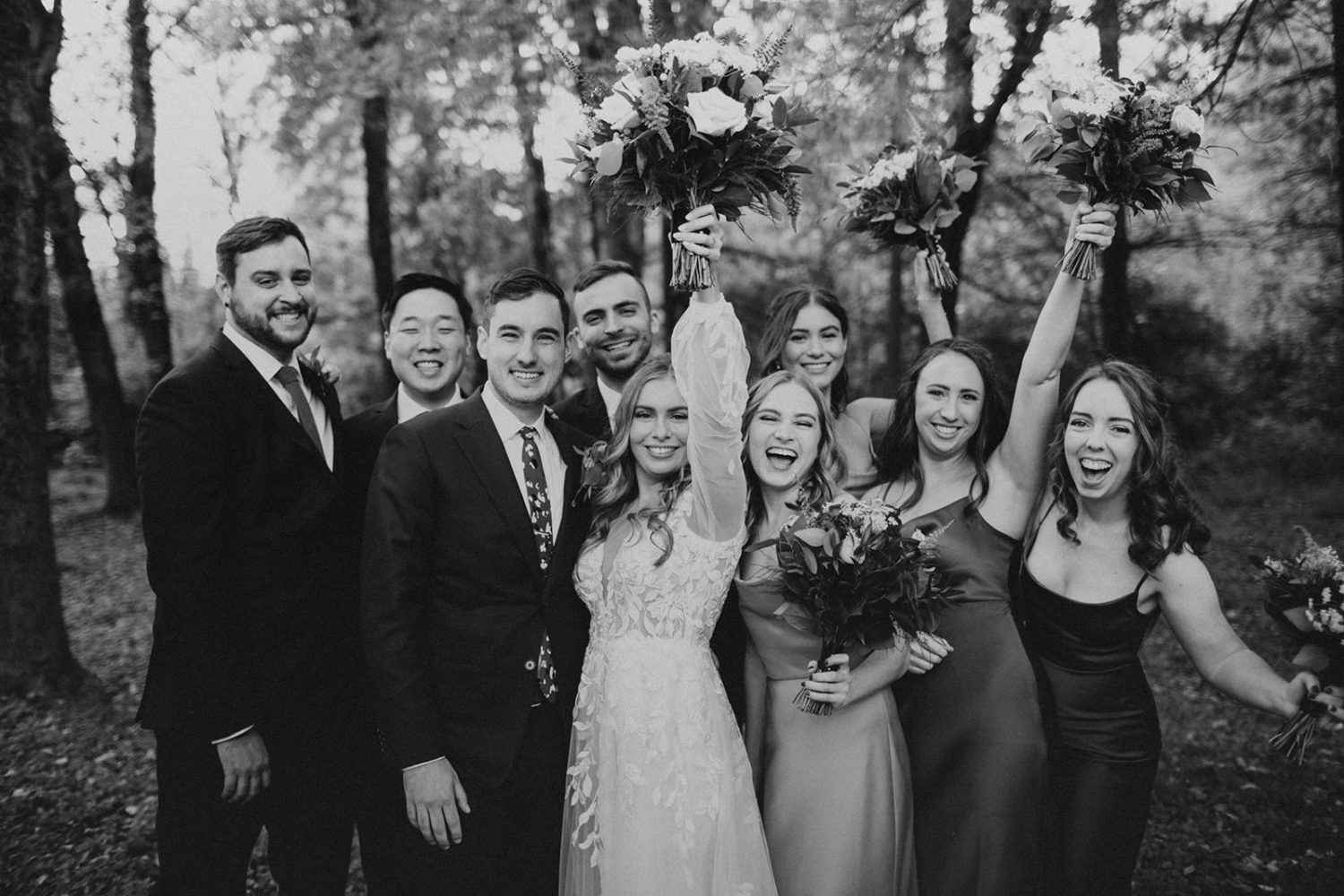 Couple cheers with wedding party and wedding bouquets at backyard wedding 