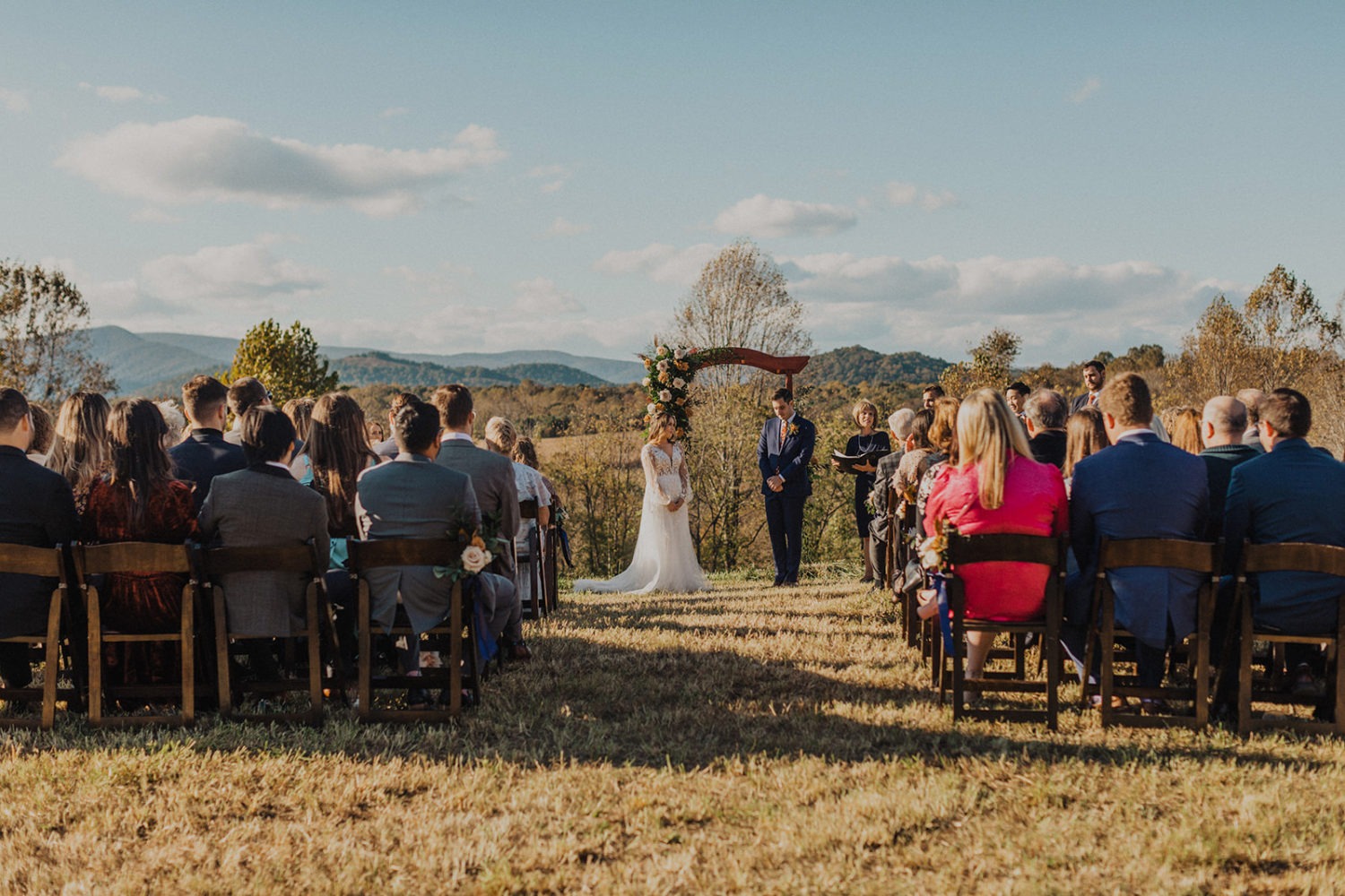 Couple stands under wedding arch at Virginia backyard wedding ceremony