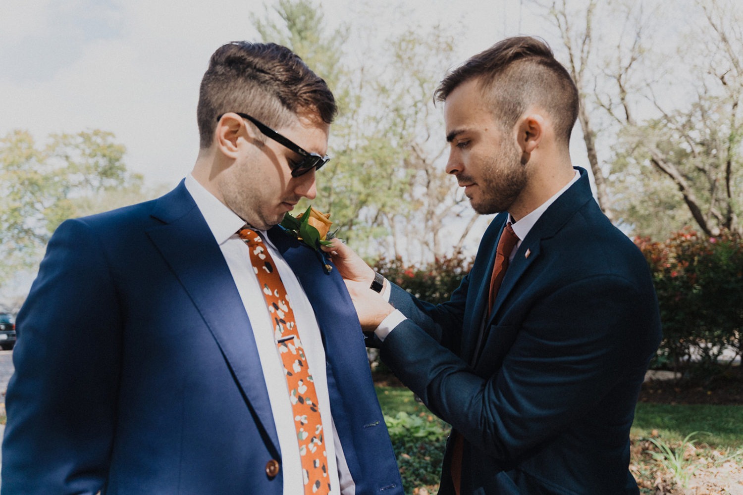 Groom puts on boutonnière getting ready at backyard wedding 