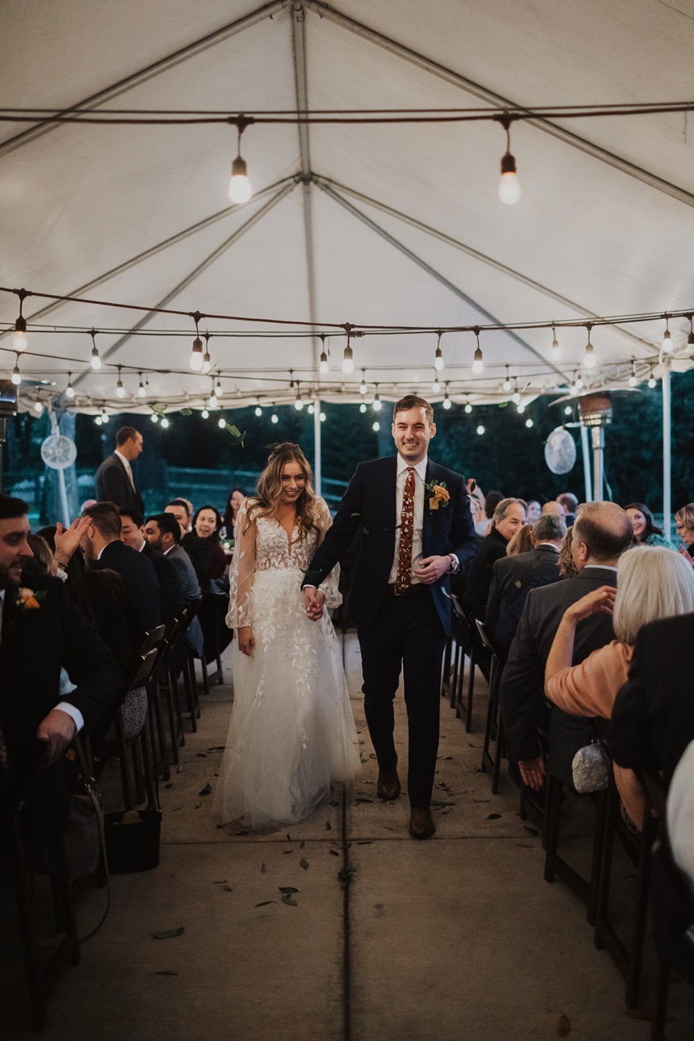 Couple walks into reception tent lit with twinkle lights