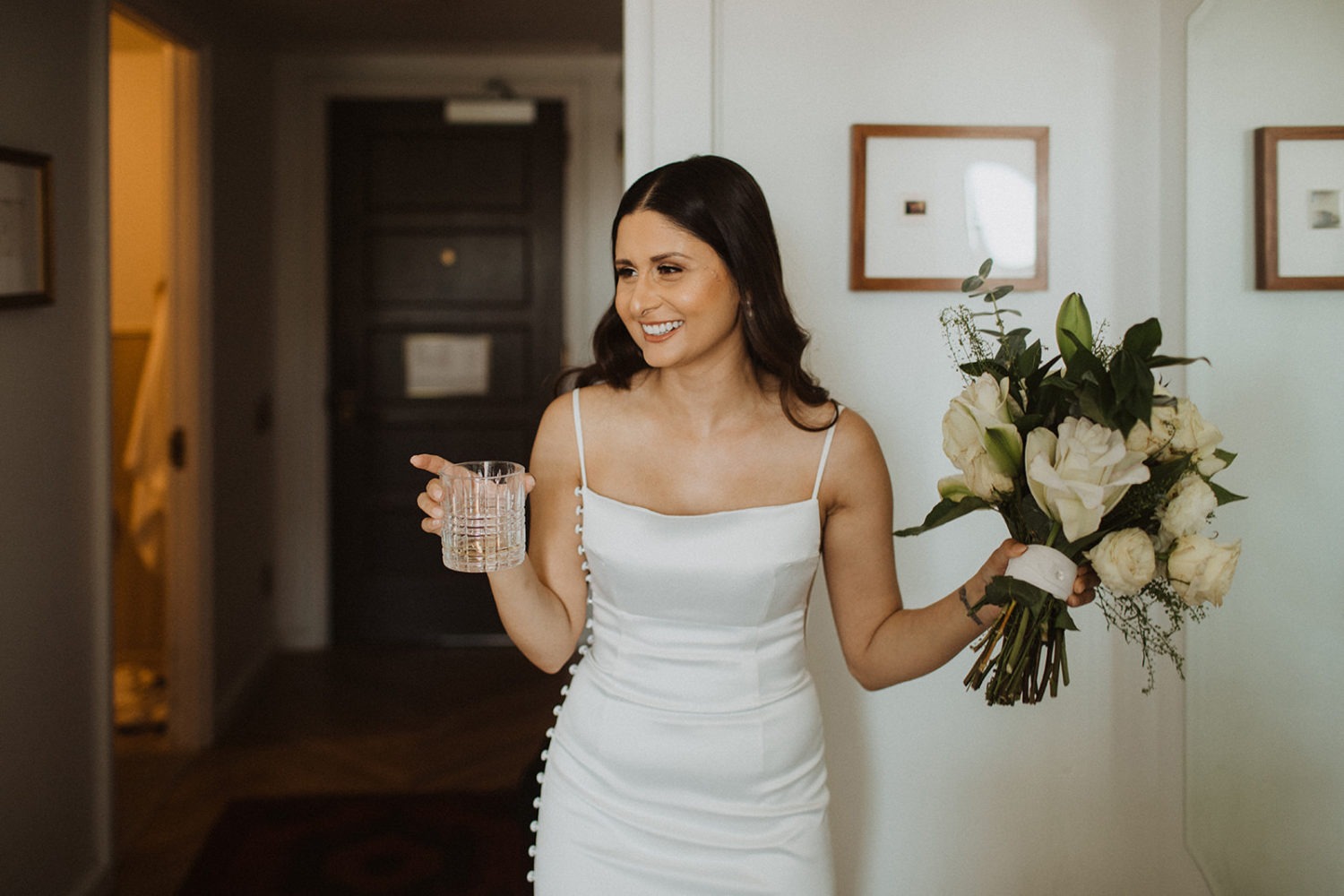 Bride holds champagne and wedding bouquet at DC rooftop hotel elopement