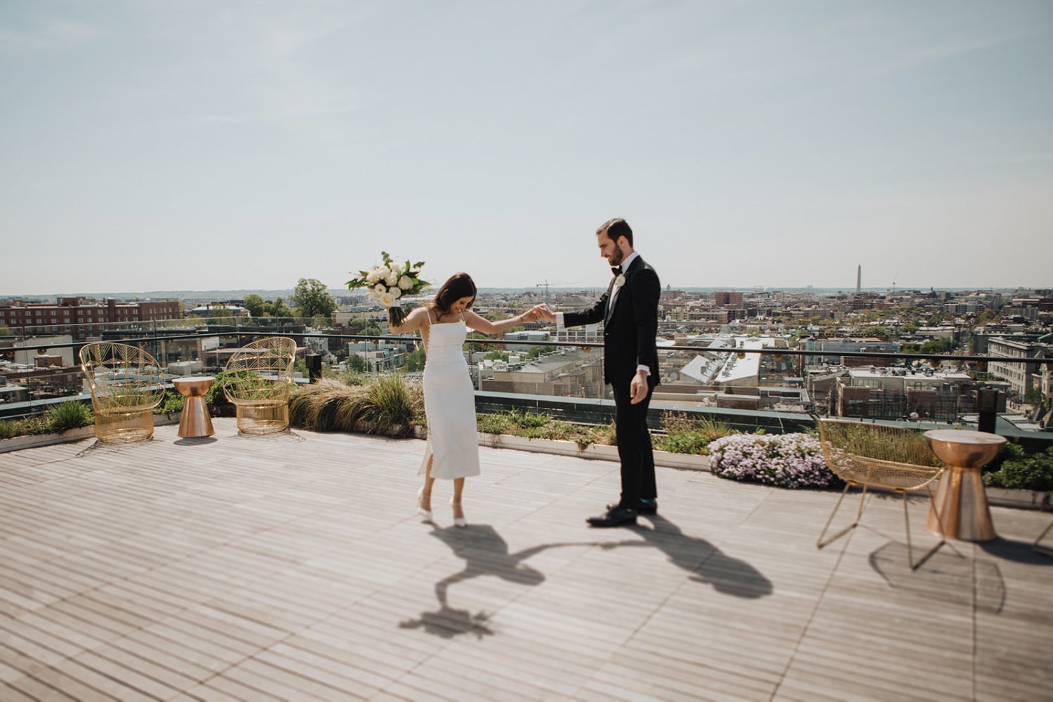 Couple holds hands with wedding bouquet at DC rooftop hotel elopement