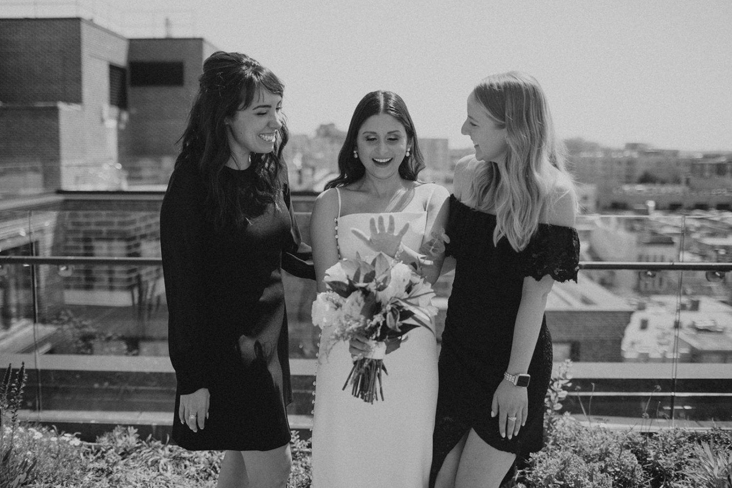 Bride shows off engagement ring to bridesmaids at DC rooftop elopement