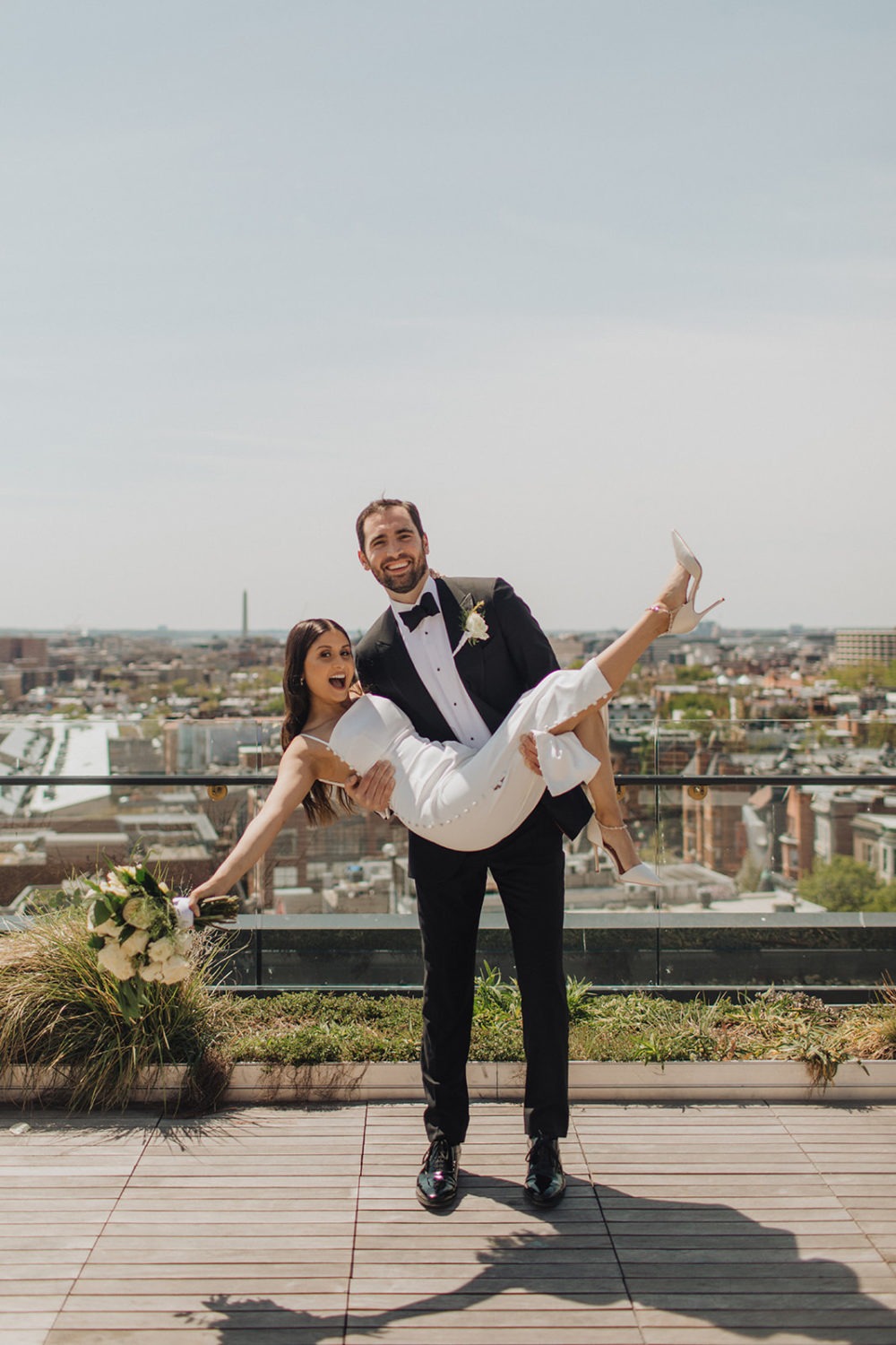 Groom carries bride at DC rooftop elopement