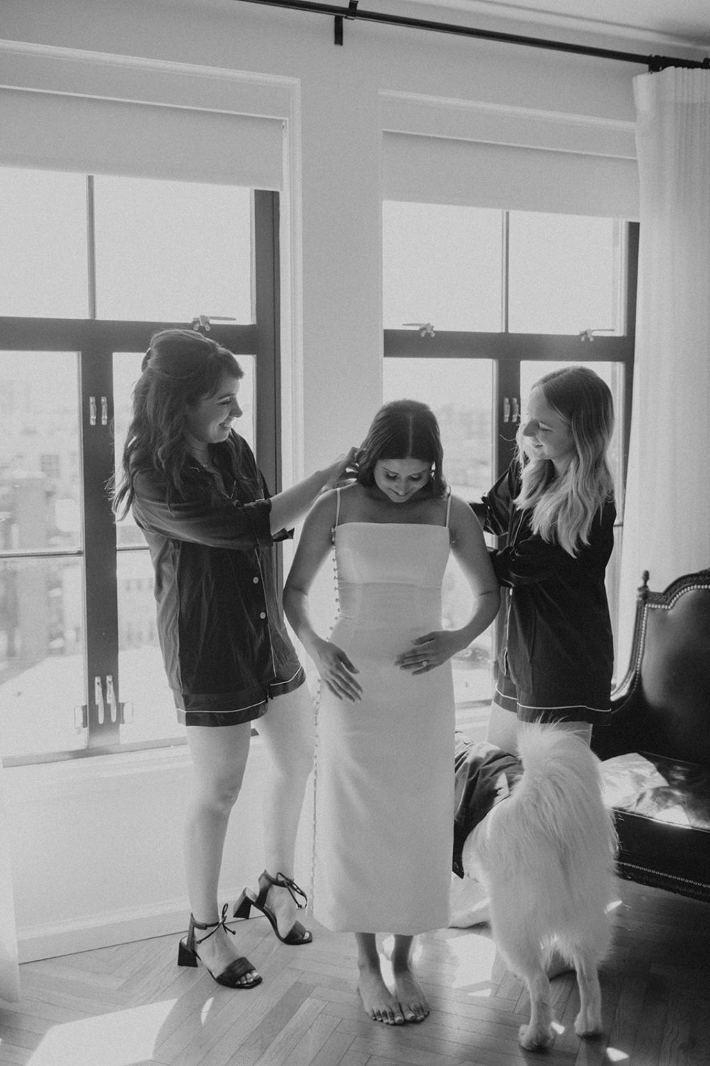 Bridesmaids help bride put on dress at DC hotel elopement