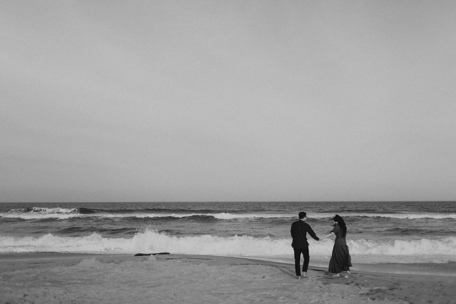 Couple runs along the beach holding hands at spring engagement session