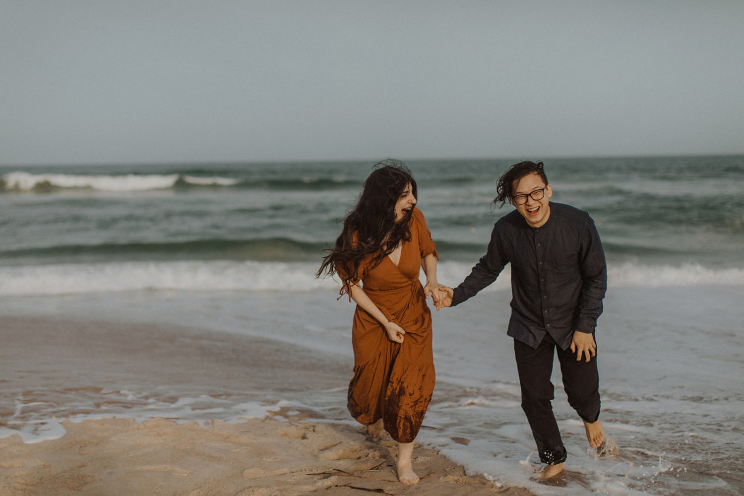 Couple runs through water at beach engagement session