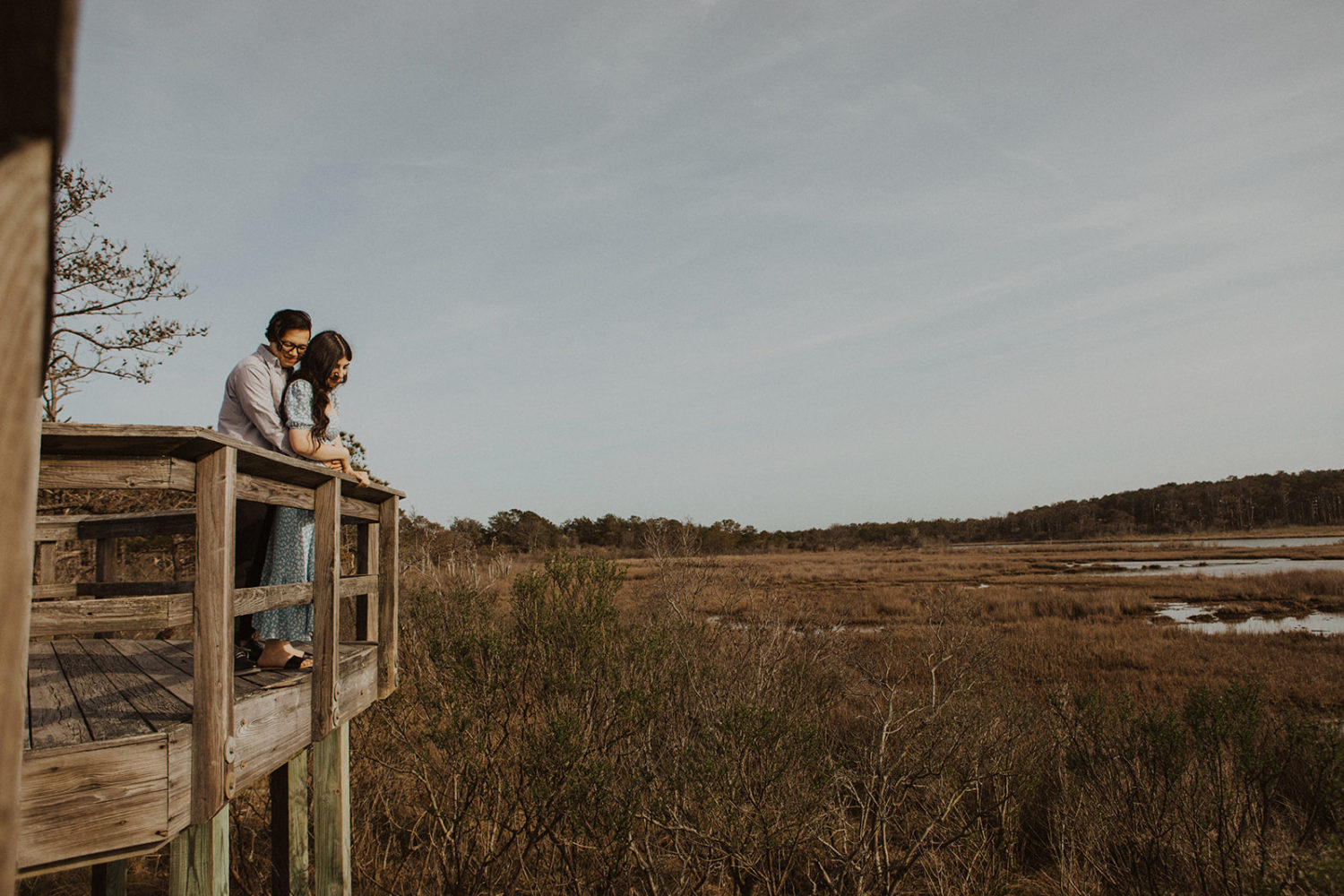Couple embraces while overlooking marsh at Assateague Island engagement session