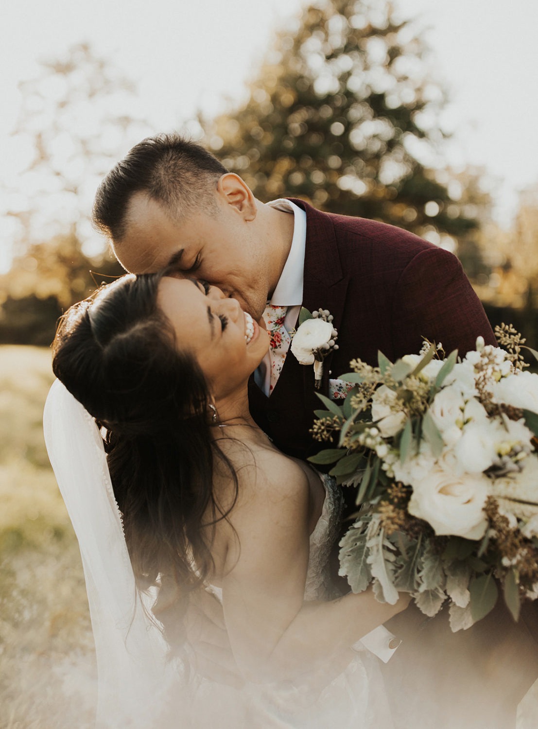 Couple kisses while holding wedding bouquet at wedding vow renewals