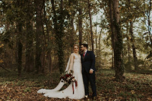 Couple stands kissing in forest wedding