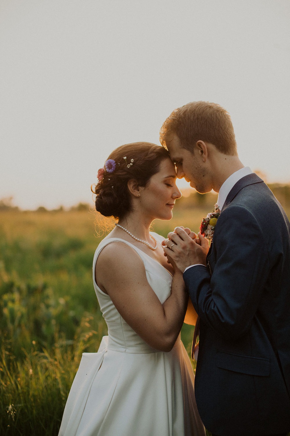 Couple embraces in a sunset field at nature wedding venue