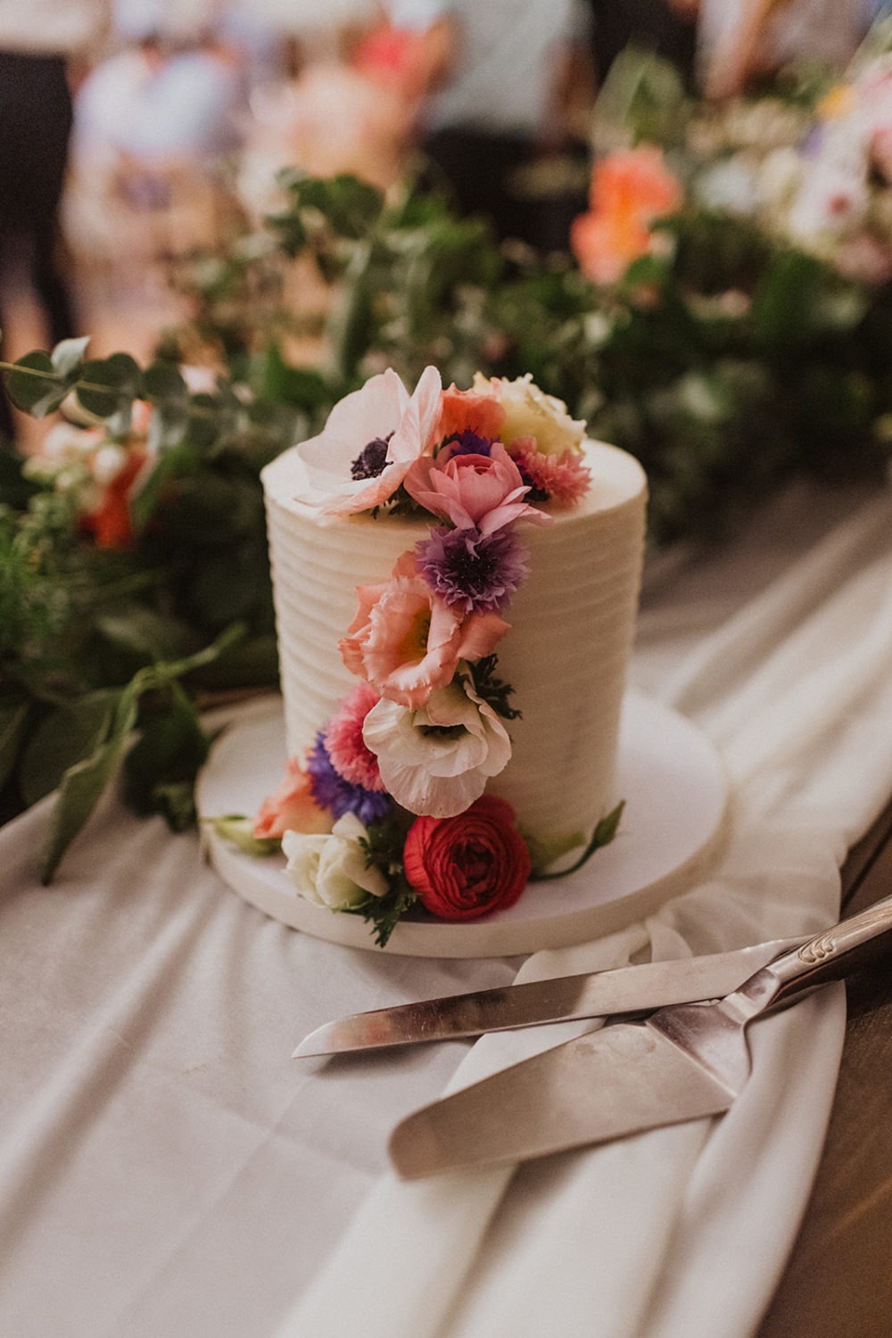 Flowers decorate white wedding cake at nature wedding venue