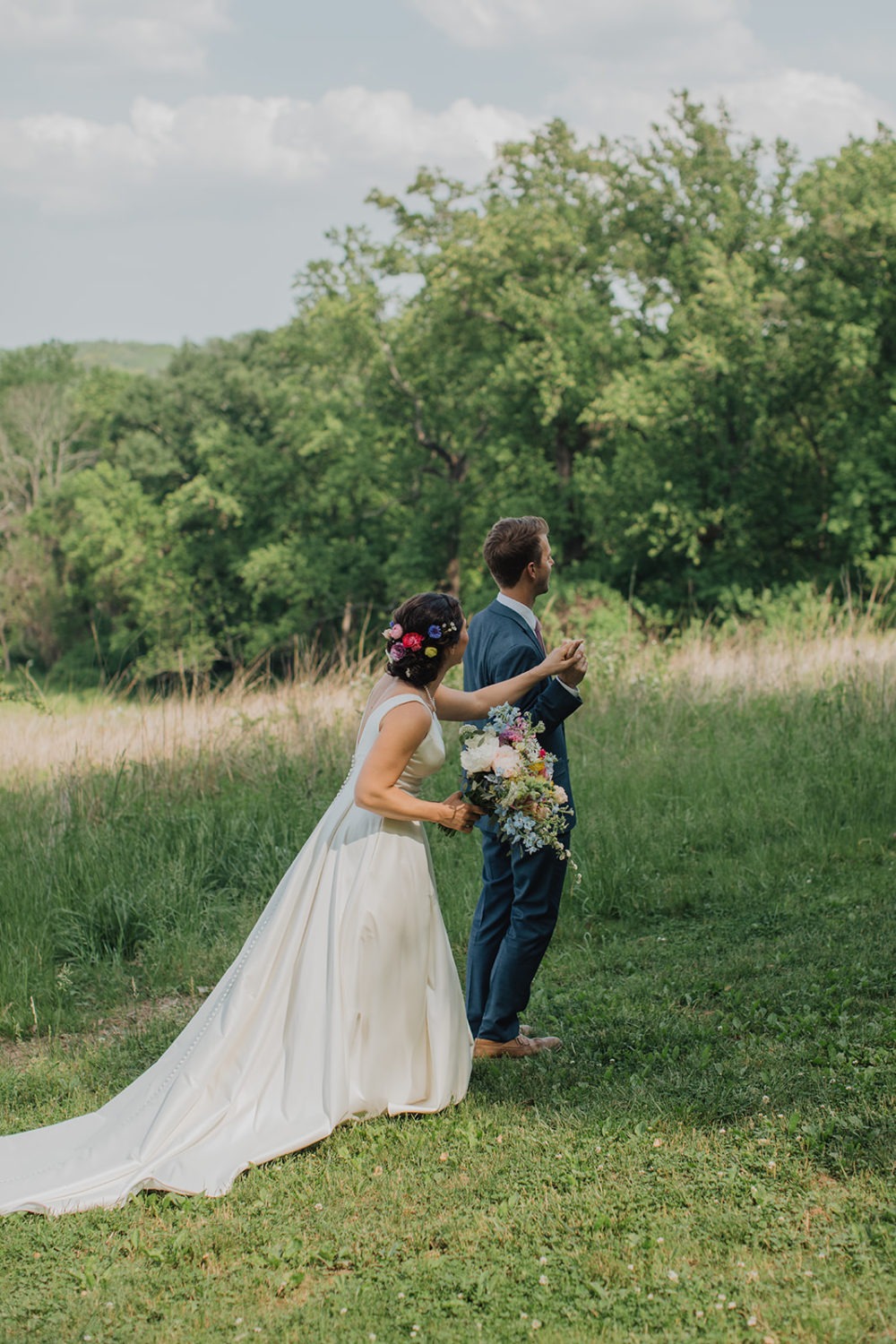 Bride holds groom's hand at nature center first look