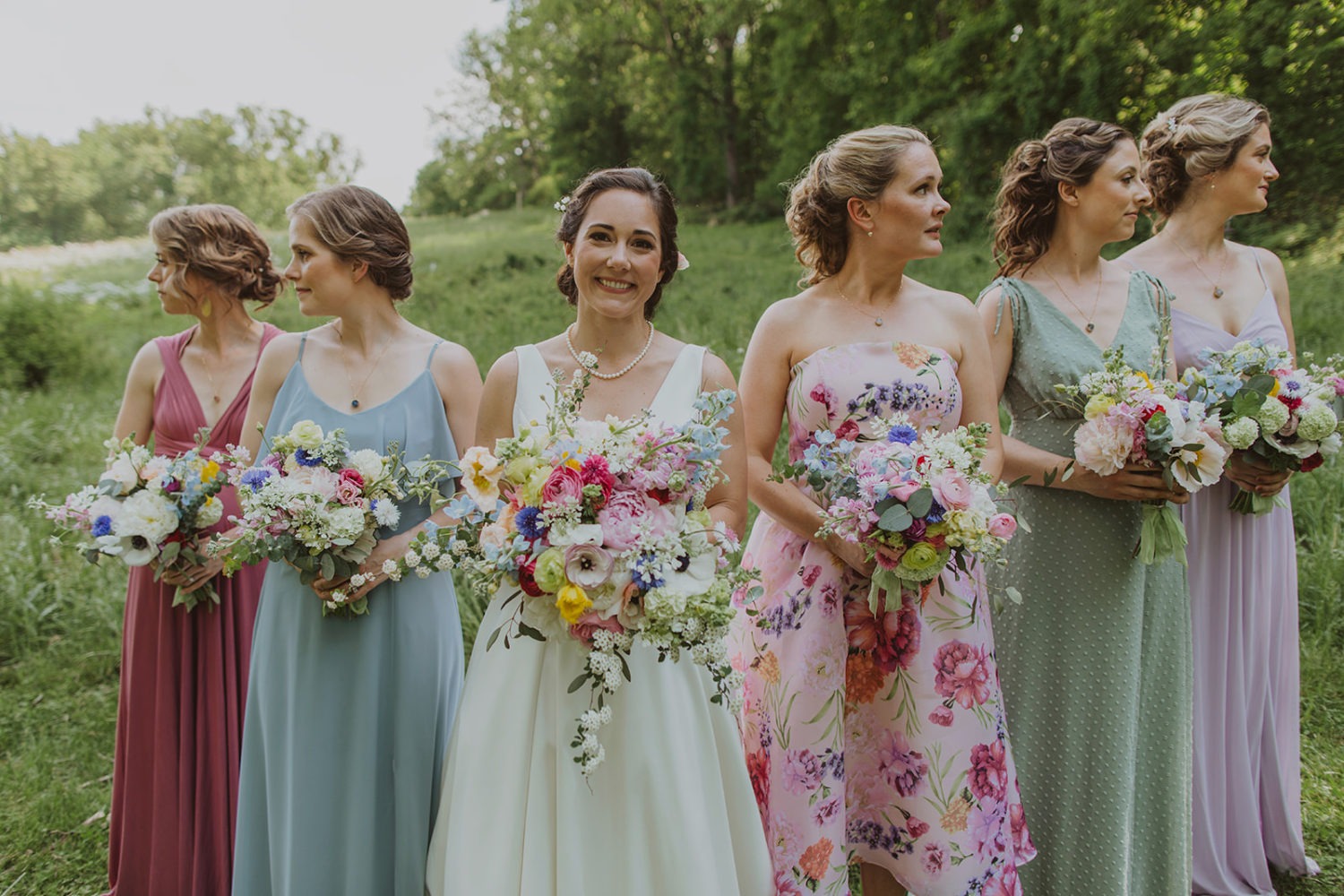 Bride holds wildflower bouquet with bridesmaids