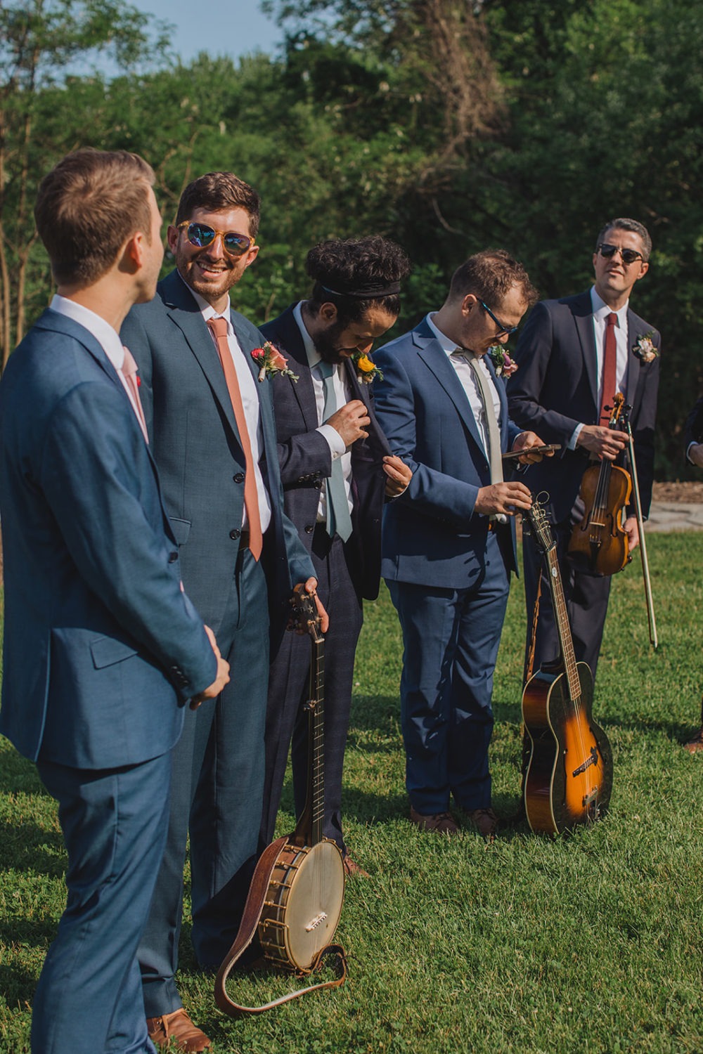 Groomsmen hold instruments while standing beside groom during ceremony