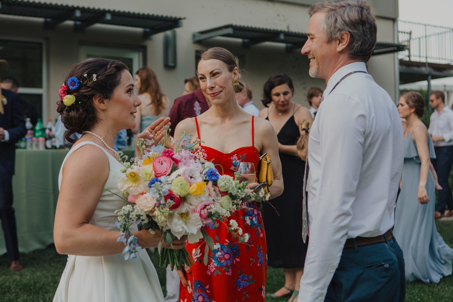 Bride holds wildflower bouquet while talking with guests