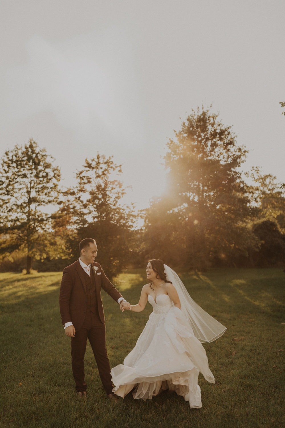 Couple holds hands walking through sunset field at Virginia wedding venue