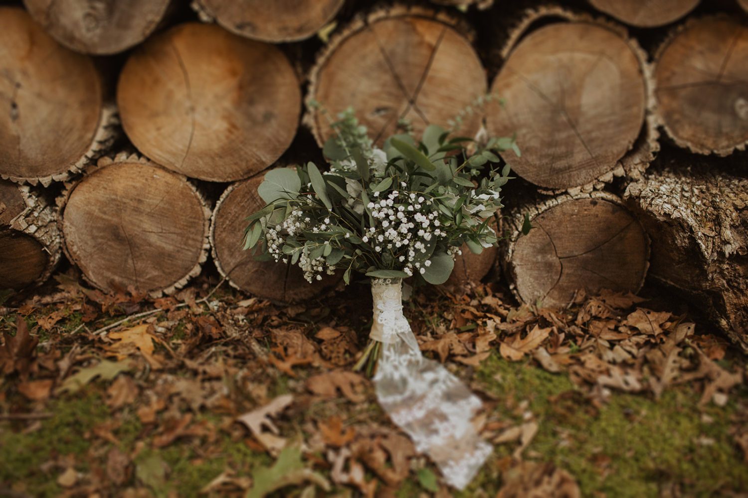 Wedding bouquet sits in front of woodpile