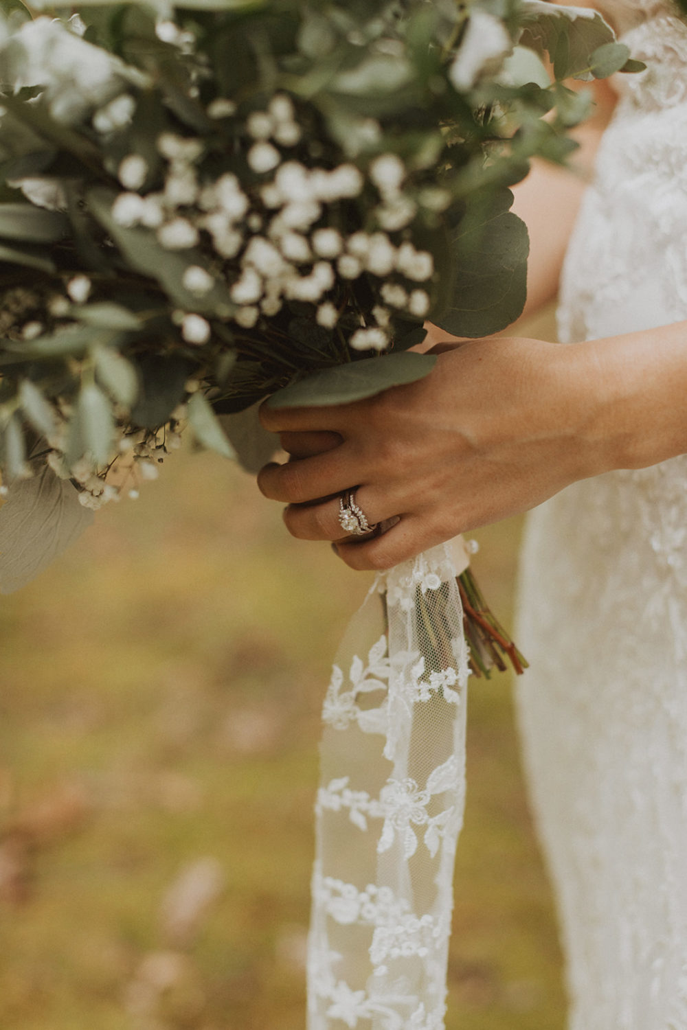 Bride holds bouquet wrapped with lace