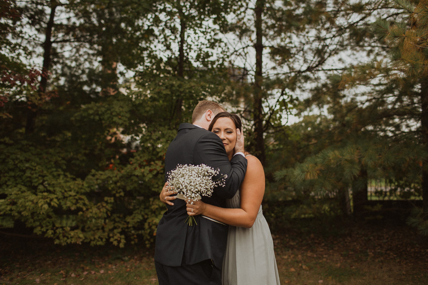 Groom hugs bridesmaid during family portraits