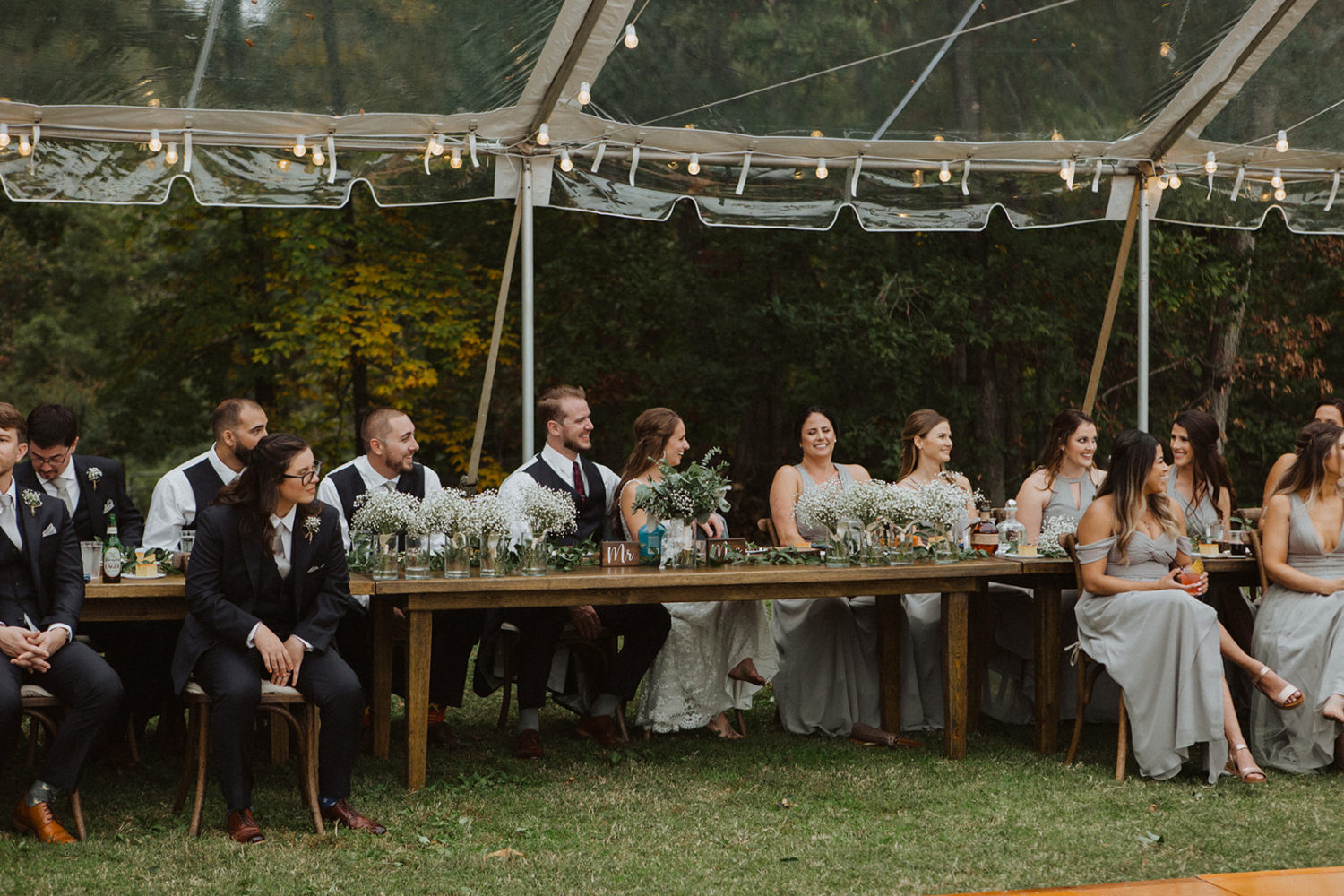 Couple laughs with wedding party at head table