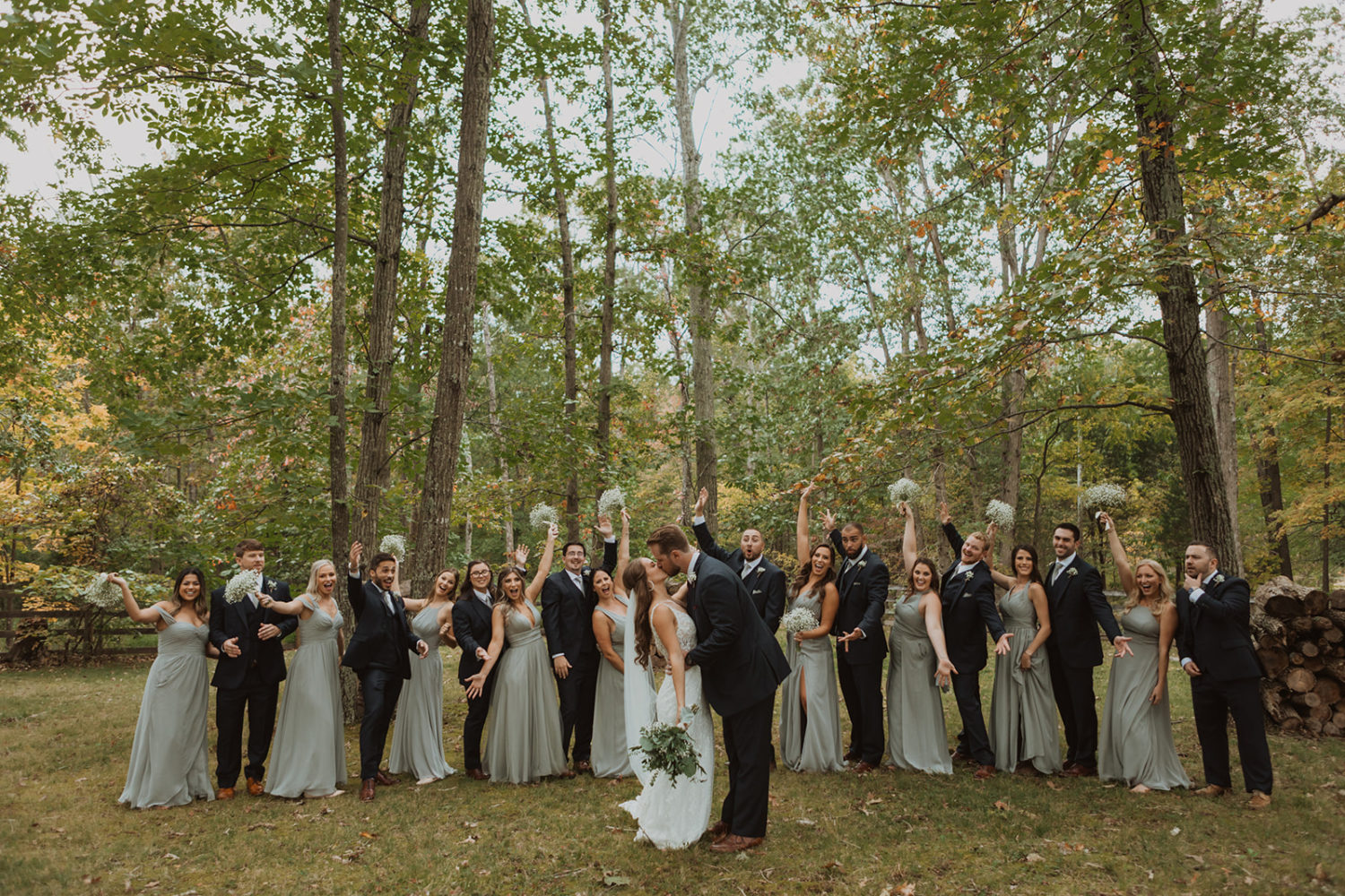 Couple kisses in front of cheering wedding party at backyard wedding