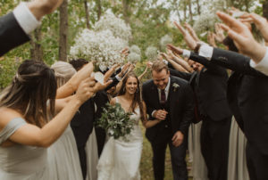 Couple walks between raised hands of wedding party