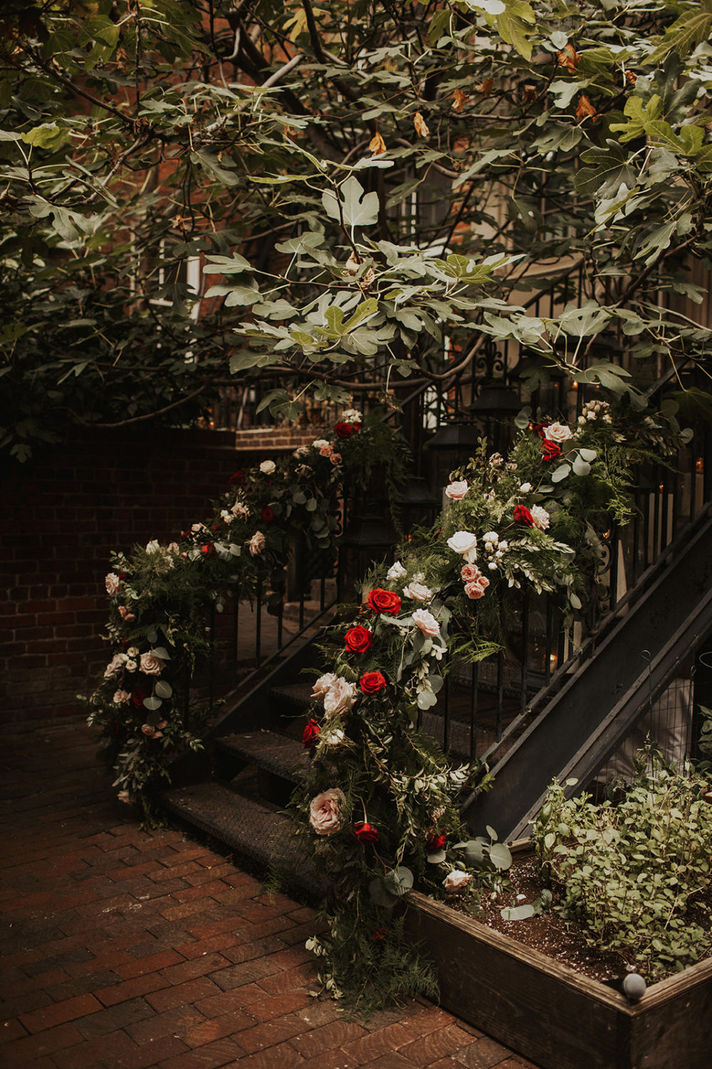 Pink and red roses cover staircase railing at outdoor Washington DC wedding
