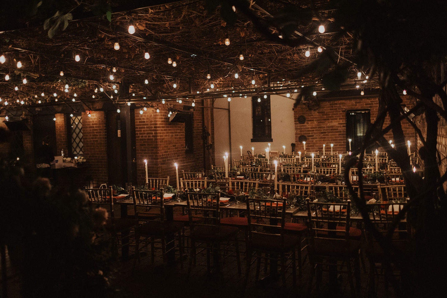 Reception tables lit by candlelight under twinkle light ivy covering at Iron Gate Restaurant DC wedding