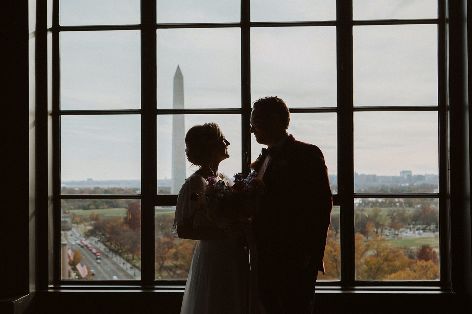 Couple stands in window overlooking Washington Monument