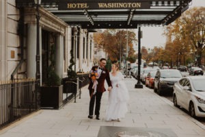 Couple walks underneath Hotel Washington sign