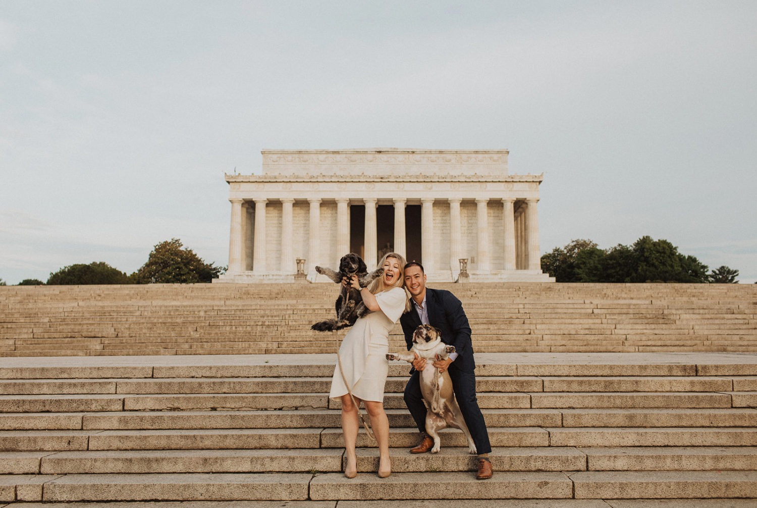 Couple holds dogs in front of Lincoln Memorial captured by DC engagement photographer