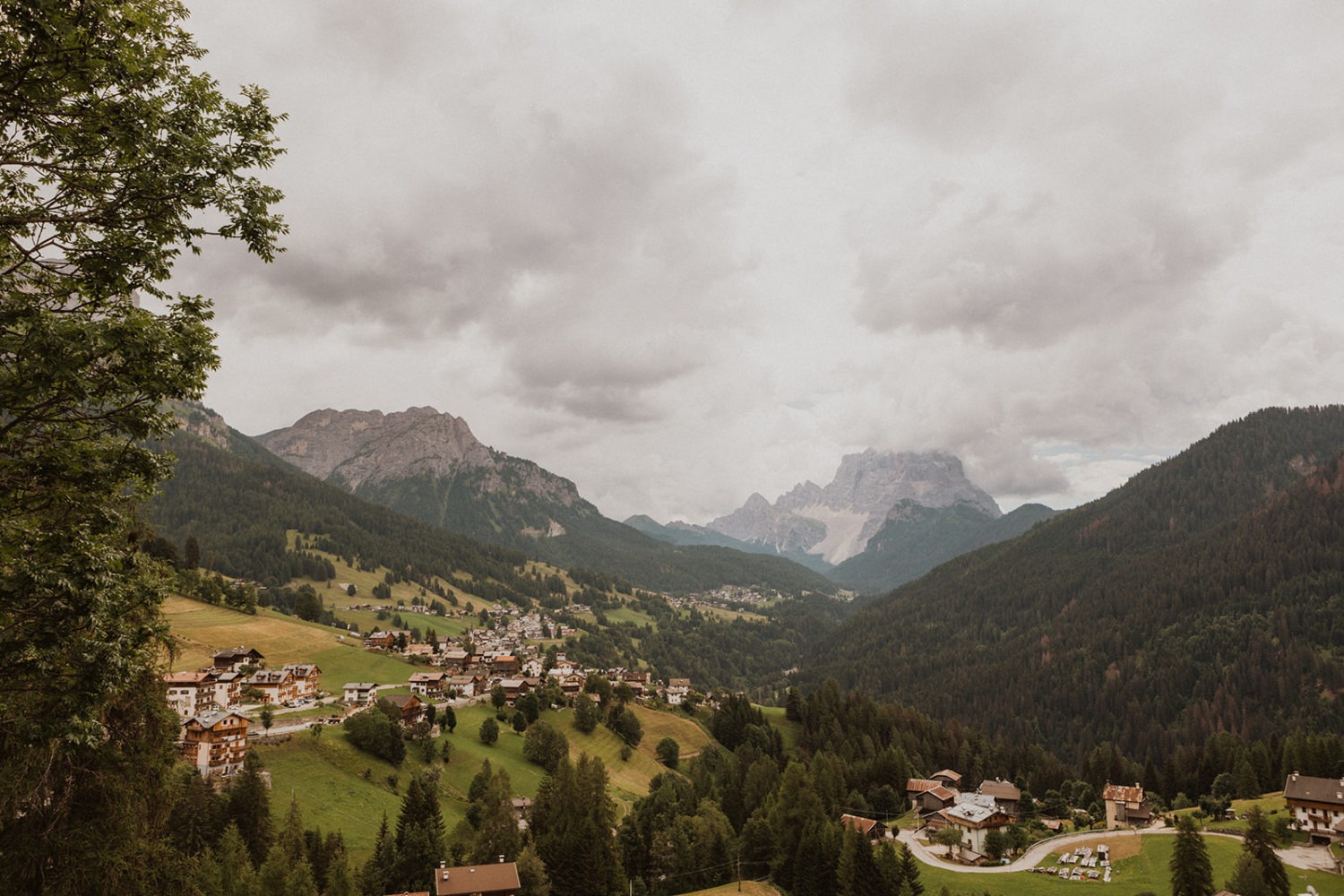 Village underneath cloud-covered dolomites in Italy captured by destination wedding photographer 