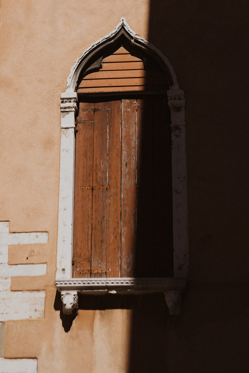 Closed window covered half in shadow in Italy town