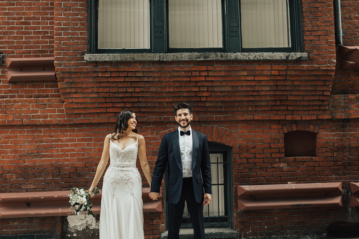 Couple stands in front of brick wall holding hands at DC wedding