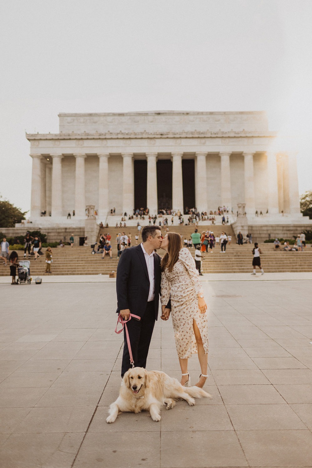 Couple kisses while holding dog's leash in front of Lincoln Memorial steps