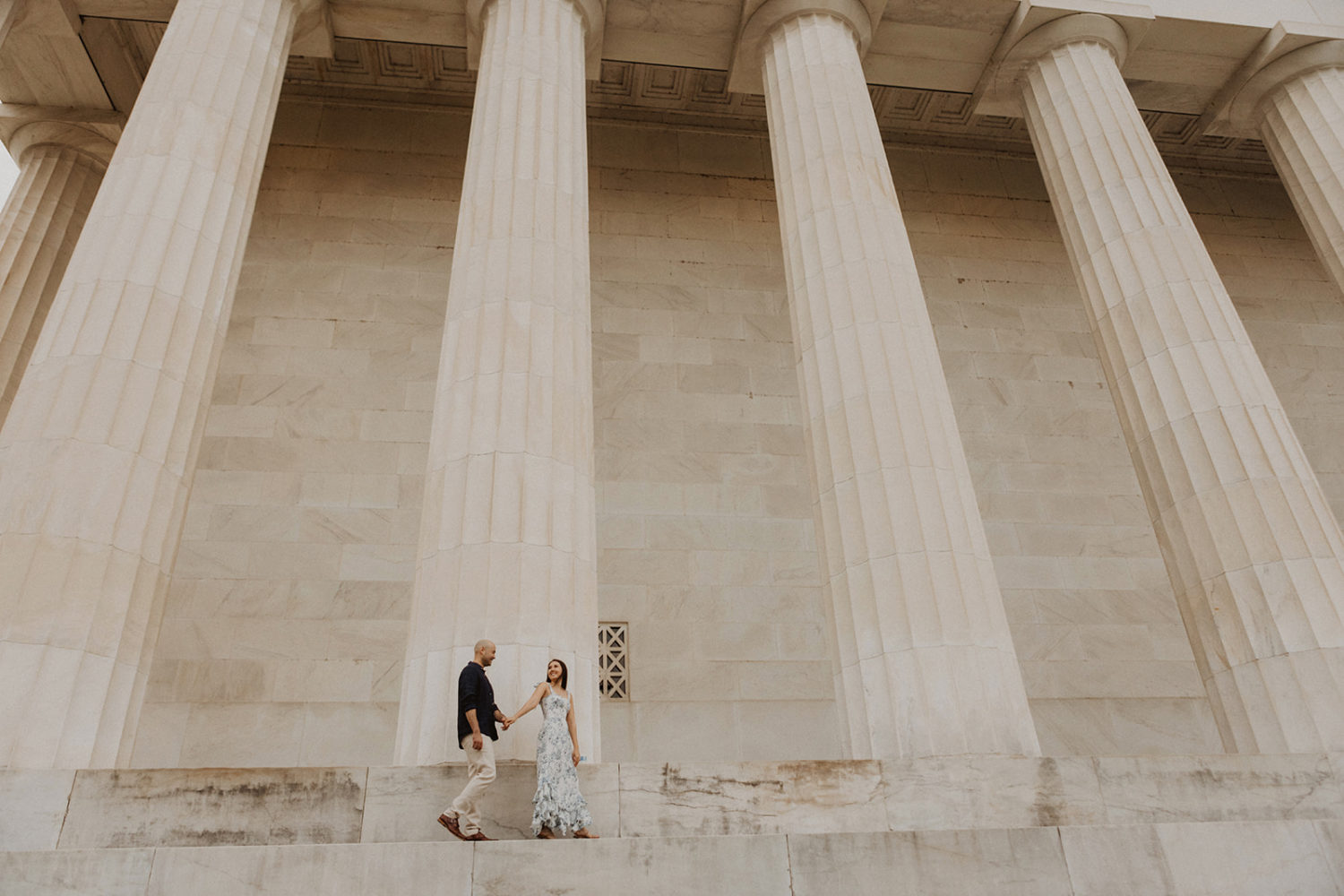 Couple walks along columns at DC engagement session