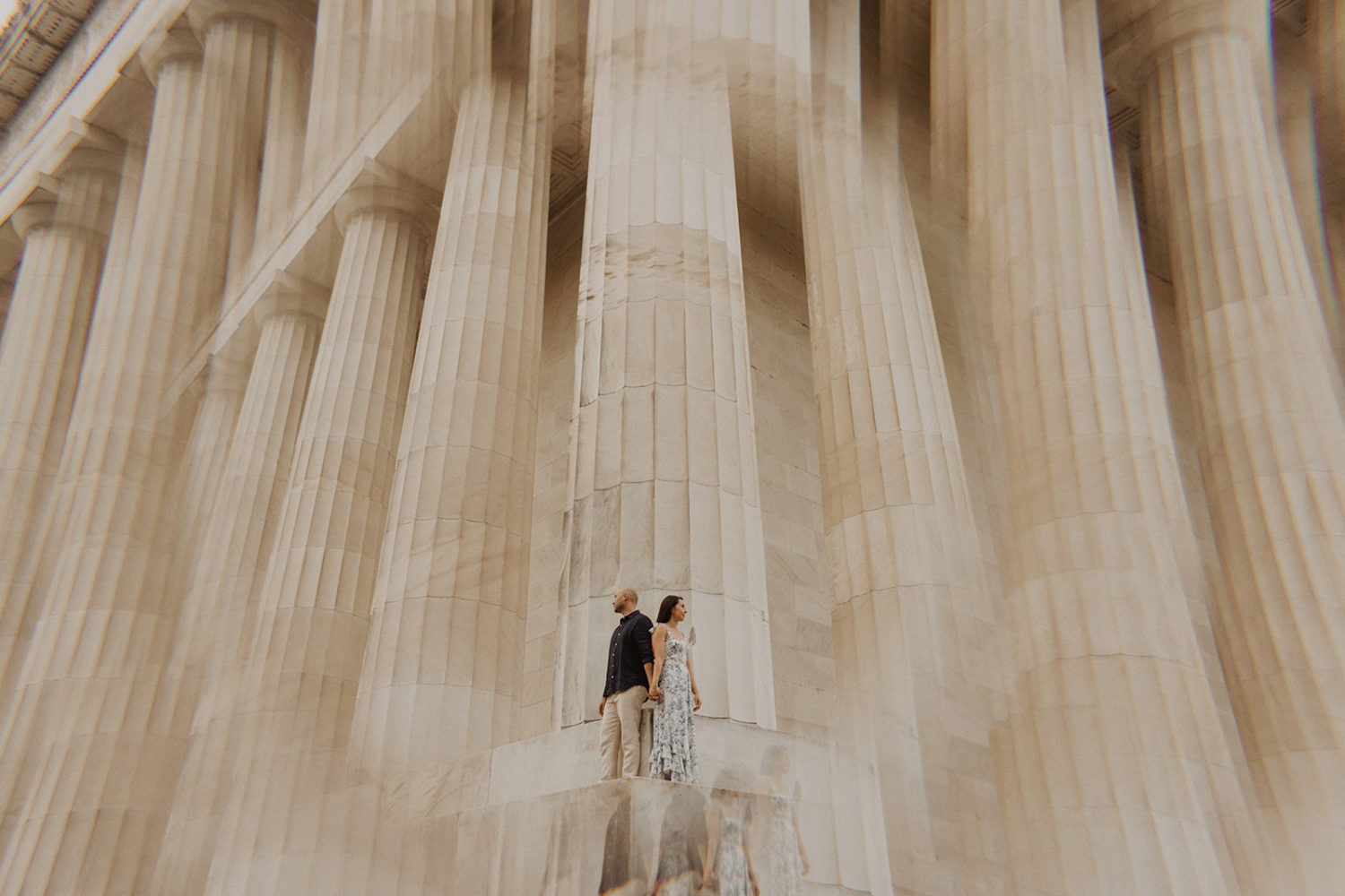 DC engagement photographer takes artsy photo of couple standing beside Lincoln Memorial columns