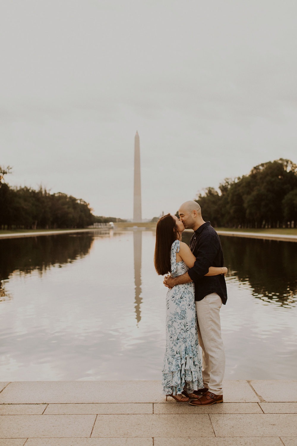 Couple kisses by Reflecting Pool at sunrise engagement session