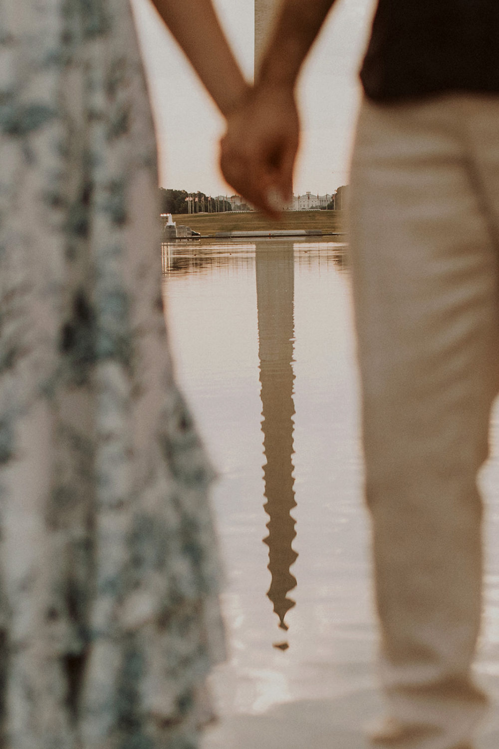 Couple holds hands beside reflecting pool captured by DC engagement photographer
