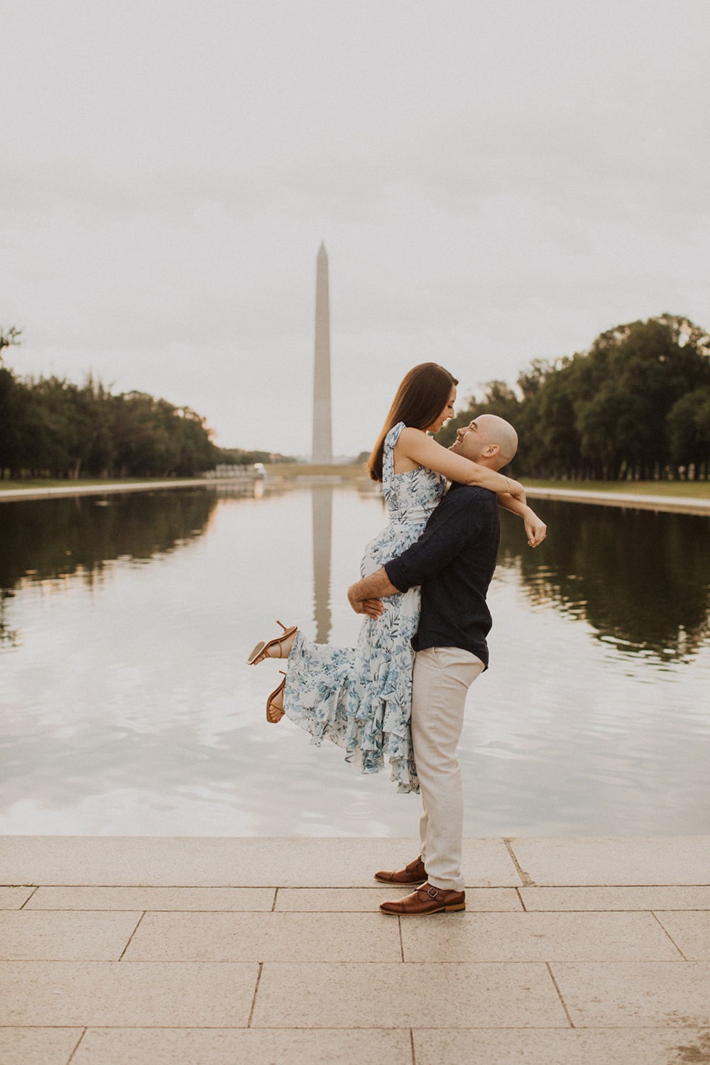 Man lifts woman by reflecting pool at sunrise DC engagement session